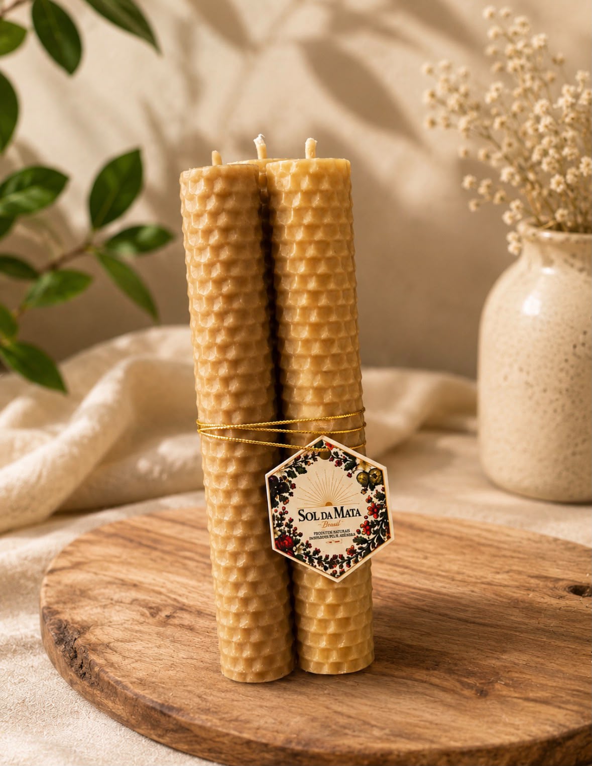 Trio de velas naturais de cera de abelha alveolada sobre linho creme.